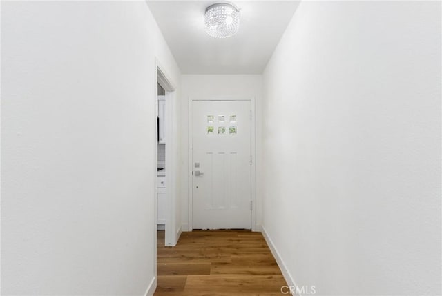 corridor featuring light hardwood / wood-style floors and an inviting chandelier