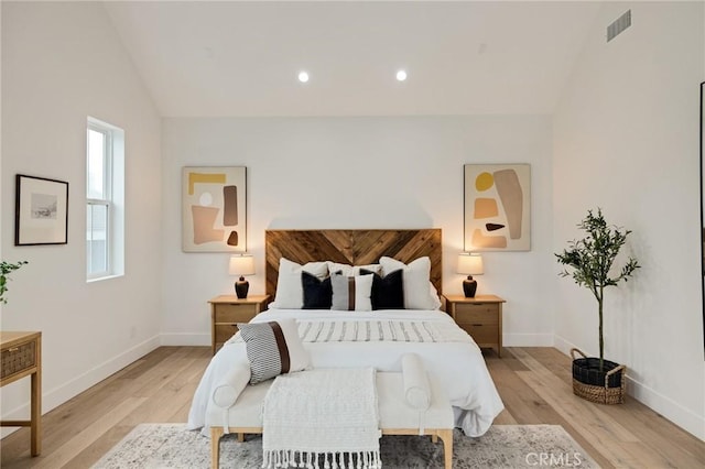 bedroom featuring baseboards, visible vents, vaulted ceiling, and light wood finished floors