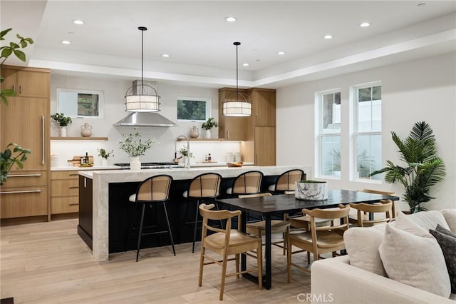 interior space featuring light wood-style flooring, recessed lighting, a kitchen breakfast bar, light countertops, and modern cabinets