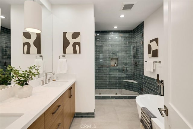 full bathroom featuring double vanity, a stall shower, visible vents, a freestanding bath, and a sink