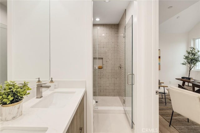 bathroom featuring double vanity, a stall shower, wood finished floors, a sink, and recessed lighting