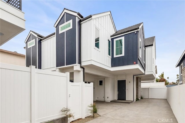 view of front of house featuring board and batten siding, a patio area, and a fenced backyard