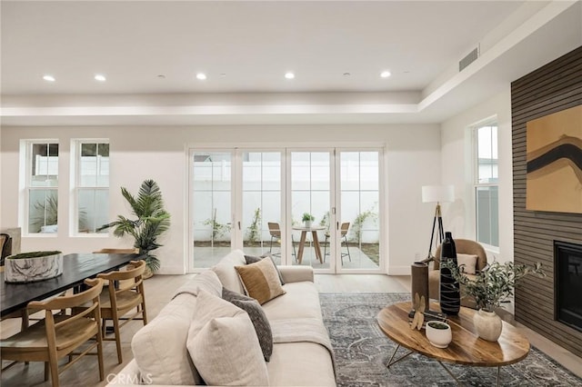 living room featuring a large fireplace, visible vents, wood finished floors, and recessed lighting