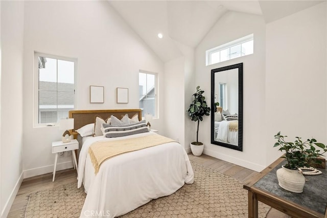 bedroom featuring high vaulted ceiling, baseboards, and wood finished floors