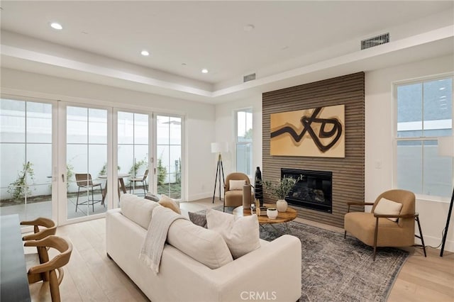 living room featuring light wood-style floors, a fireplace, visible vents, and recessed lighting