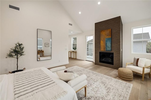 bedroom with high vaulted ceiling, recessed lighting, a large fireplace, visible vents, and light wood-type flooring