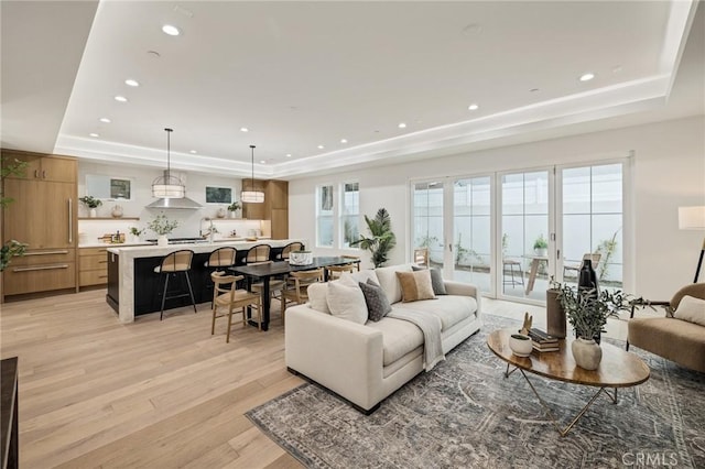 living room with recessed lighting, a raised ceiling, and light wood finished floors