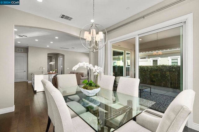 dining space featuring an inviting chandelier, sink, and dark wood-type flooring