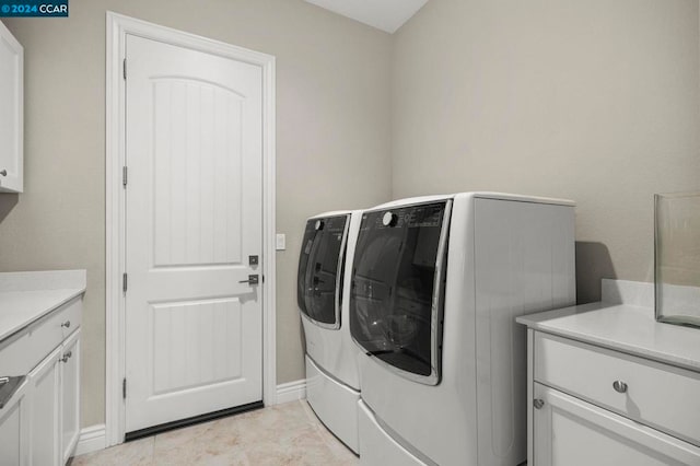 clothes washing area with washer and dryer and cabinets