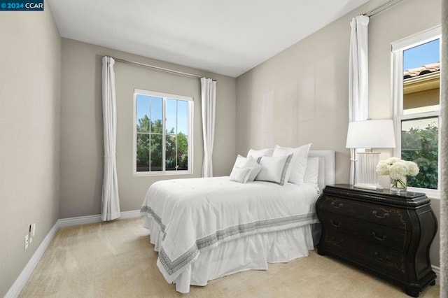 bedroom featuring light carpet and multiple windows