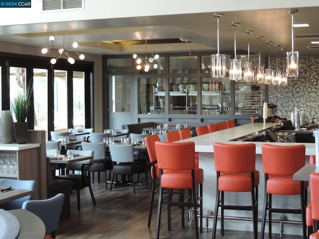 bar with dark wood-type flooring, tasteful backsplash, and hanging light fixtures