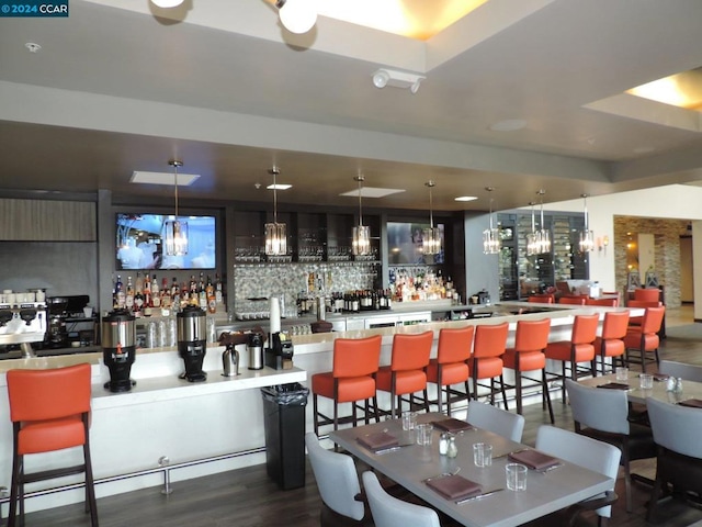 bar featuring hanging light fixtures and dark hardwood / wood-style flooring