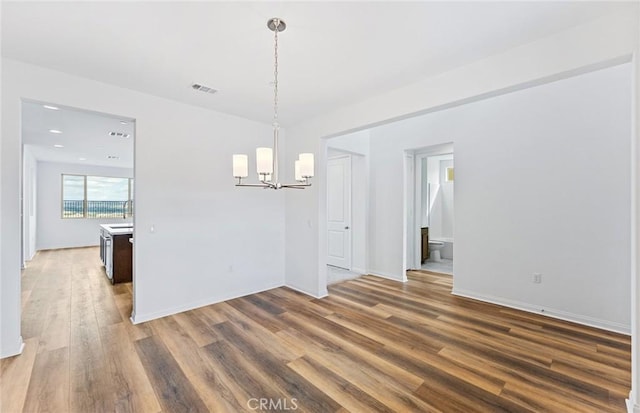 interior space with wood finished floors, baseboards, visible vents, a sink, and a notable chandelier