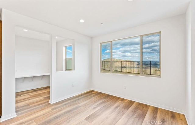 empty room featuring recessed lighting, baseboards, and light wood finished floors