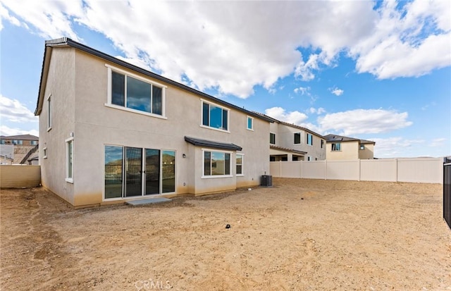 back of property with a fenced backyard, central AC, and stucco siding