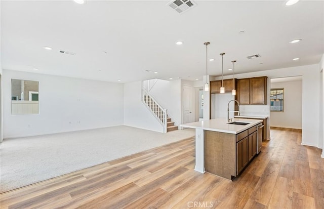 kitchen featuring a sink, visible vents, a kitchen island with sink, and light countertops