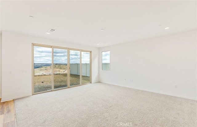 spare room featuring light carpet and baseboards