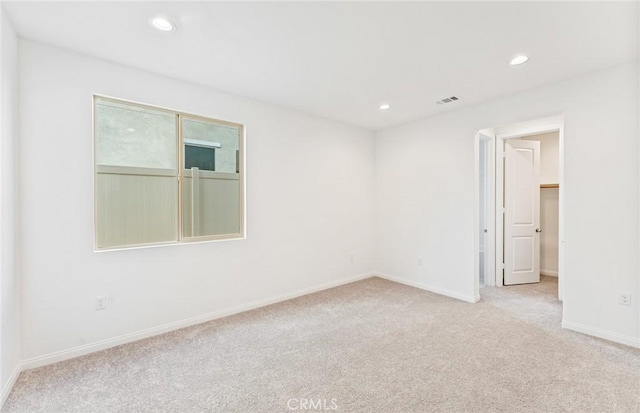 empty room featuring light carpet, visible vents, recessed lighting, and baseboards