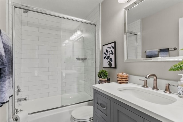 full bathroom with combined bath / shower with glass door, vanity, and toilet