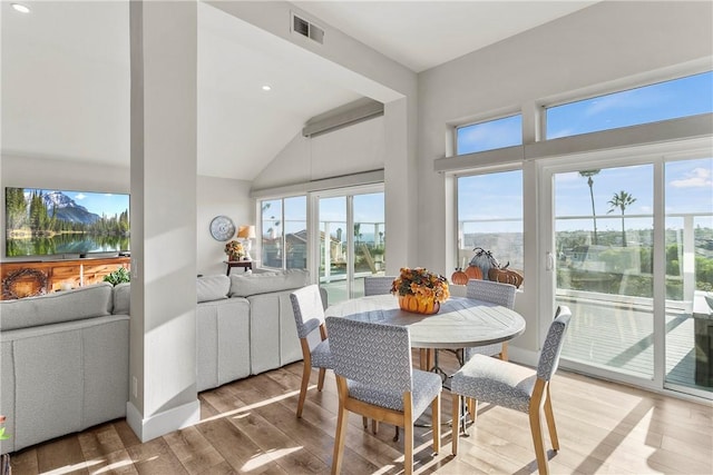 dining room with a water view, wood-type flooring, and vaulted ceiling