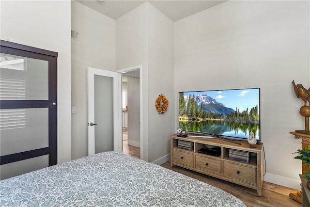 bedroom featuring a towering ceiling and hardwood / wood-style flooring