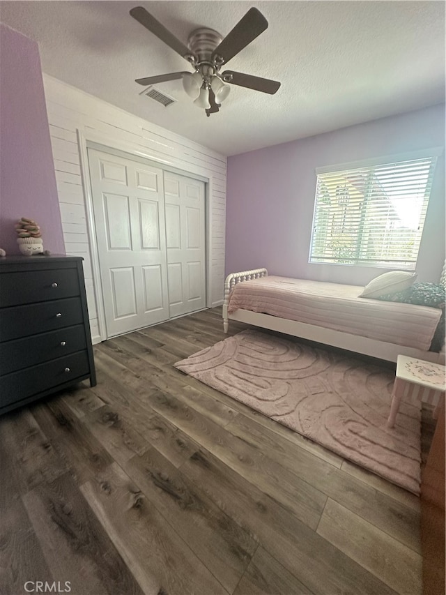 bedroom with ceiling fan, a textured ceiling, a closet, and dark hardwood / wood-style floors