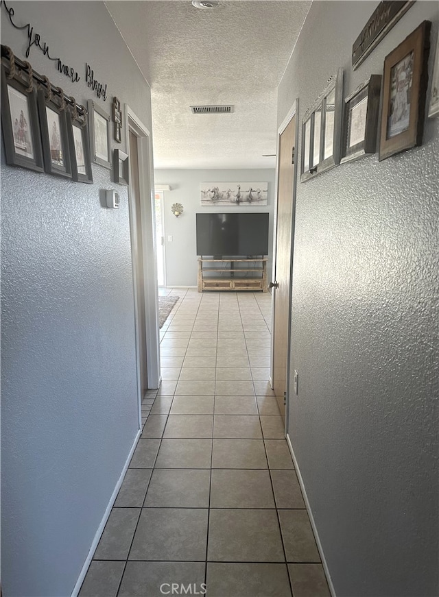 hallway with tile patterned flooring and a textured ceiling