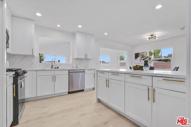 kitchen with sink, dishwasher, black gas stove, white cabinets, and light wood-type flooring