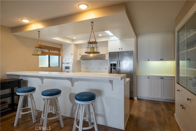 kitchen featuring a kitchen breakfast bar, decorative light fixtures, oven, and white cabinets