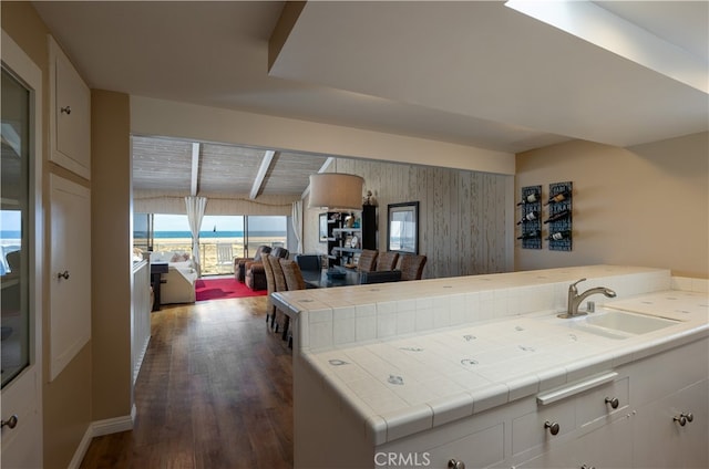 kitchen featuring white cabinets, sink, kitchen peninsula, dark hardwood / wood-style floors, and tile counters