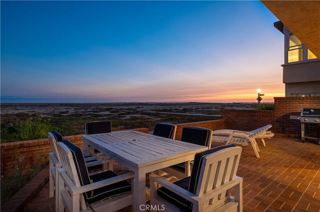 patio terrace at dusk featuring a grill