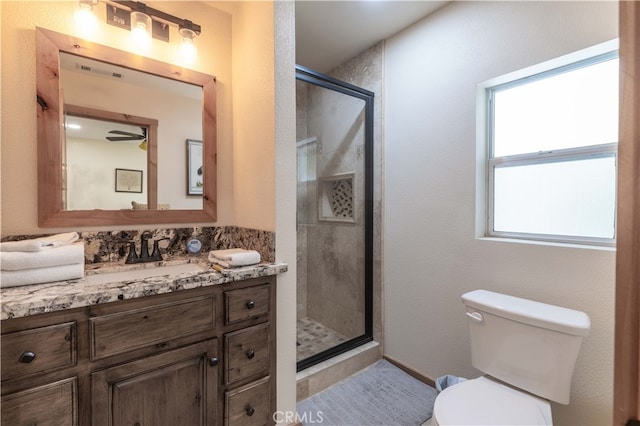 bathroom featuring a shower with door, vanity, and toilet