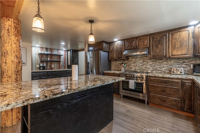 kitchen with appliances with stainless steel finishes, decorative backsplash, light stone countertops, pendant lighting, and dark brown cabinets