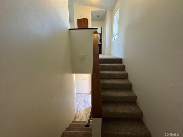 stairway featuring vaulted ceiling and wood finished floors