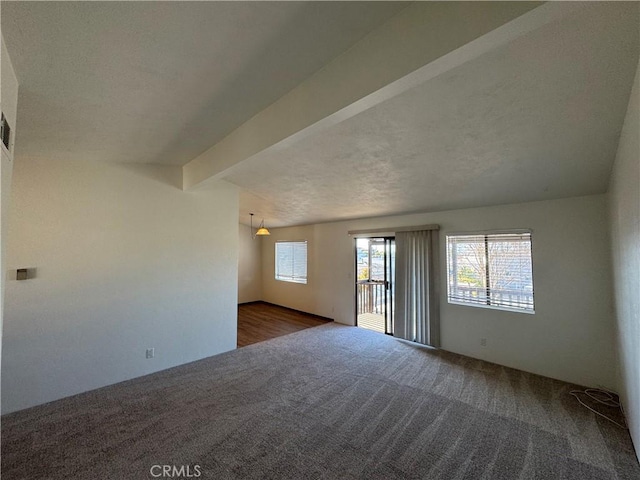 carpeted empty room with vaulted ceiling with beams