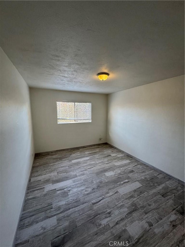 empty room featuring a textured ceiling and wood finished floors