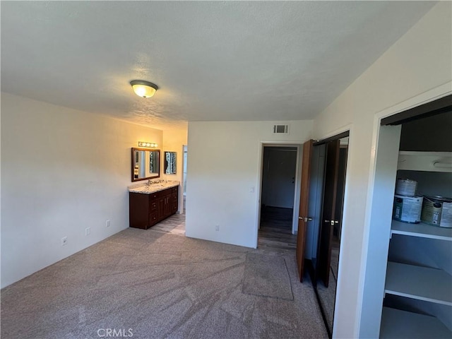 carpeted bedroom featuring visible vents and ensuite bathroom