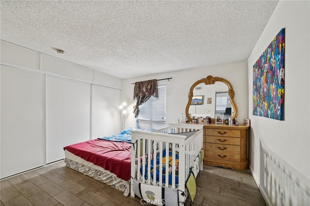 bedroom with a textured ceiling, a closet, and dark wood-type flooring