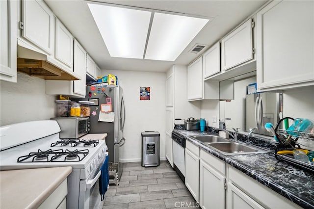 kitchen with white cabinets, stainless steel fridge, sink, white gas stove, and dishwashing machine