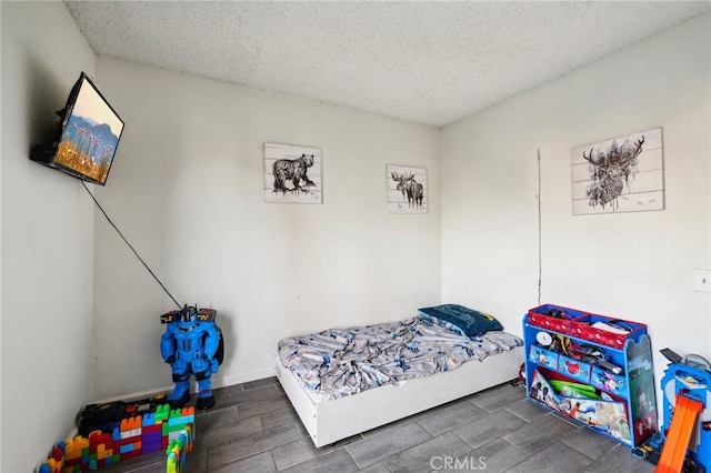 bedroom with a textured ceiling and dark hardwood / wood-style flooring