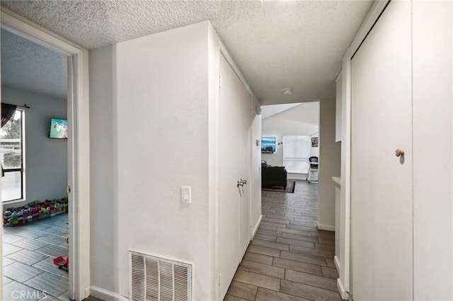 corridor with light wood-type flooring and a textured ceiling