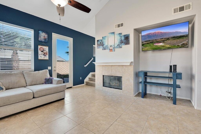 tiled living room with ceiling fan, a fireplace, and high vaulted ceiling