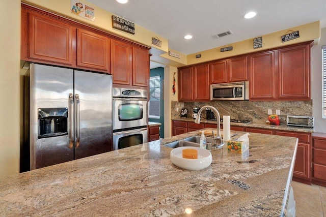 kitchen with light stone counters, sink, and appliances with stainless steel finishes