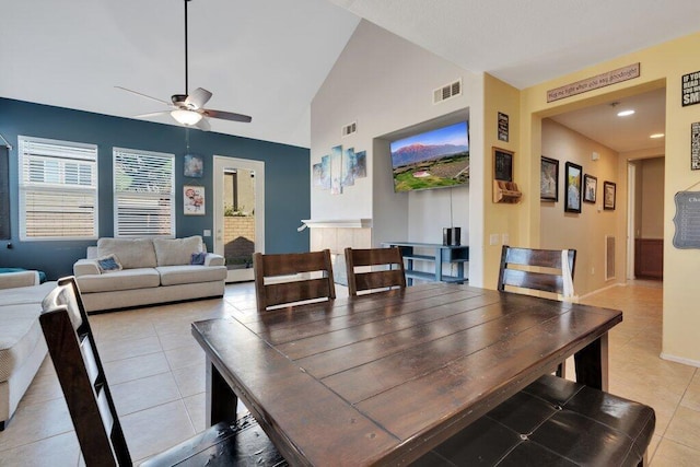 tiled dining room featuring a tile fireplace, ceiling fan, and lofted ceiling