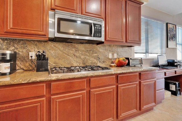 kitchen featuring decorative backsplash, light stone counters, light tile patterned floors, and appliances with stainless steel finishes