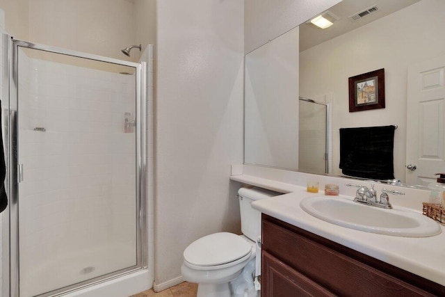 bathroom featuring tile patterned flooring, vanity, toilet, and a shower with shower door