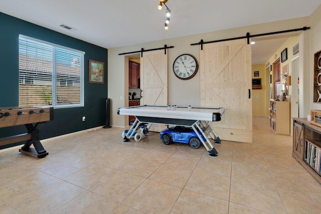 recreation room featuring a barn door and light tile patterned flooring