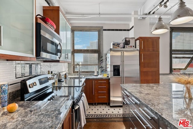 kitchen featuring dark stone countertops, stainless steel appliances, sink, and tasteful backsplash