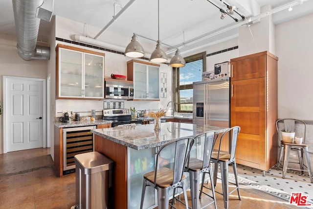 kitchen with appliances with stainless steel finishes, decorative backsplash, wine cooler, light stone countertops, and decorative light fixtures