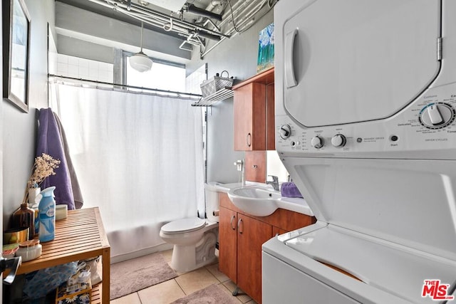 clothes washing area featuring sink, light tile patterned floors, and stacked washer and clothes dryer